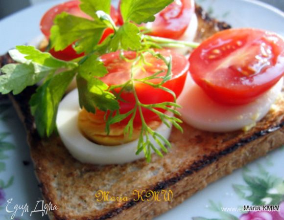 Зубчики чеснока разрезать на половинки и ими натереть ещё горячий хлебушек. Смазать майонезом, уложить на хлебцы яйца, помидорки, поперчить, посолить и украсить зеленью. 
Приятного аппетита.

