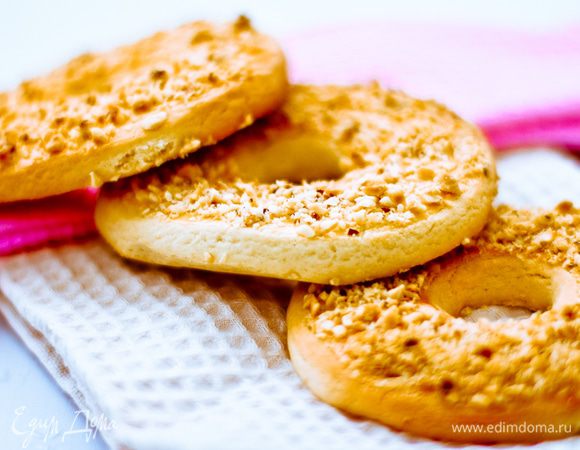 Смешиваем миксером на средней скорости масло, 1 яйцо, сахарную пудру, разрыхлитель и соль. Всыпаем муку, продолжаем мешать 10-20секунд, пока не получатся крошки. Руками слепливаем крошки в мягкий комок. Кладем тесто в холодильник на 20 минут.

После холодильника раскатываем тесто в пласт толщиной 6-7 мм. Вырезаем кусочки и делаем в каждом небольшой отверстие. Ставим противень с колечками в морозилку на 20 минут.

На тарелку насыпаем измельченные орехи, в чашку вливаем желток и разбалтываем кисточкой. Подмороженные колечки смазываем желтком и переворачиваем смазанной стороной на орехи.

Укладываем колечки на противень, застеленный пергаментной бумагой, и печем 12 минут при температуре 200 градусов.