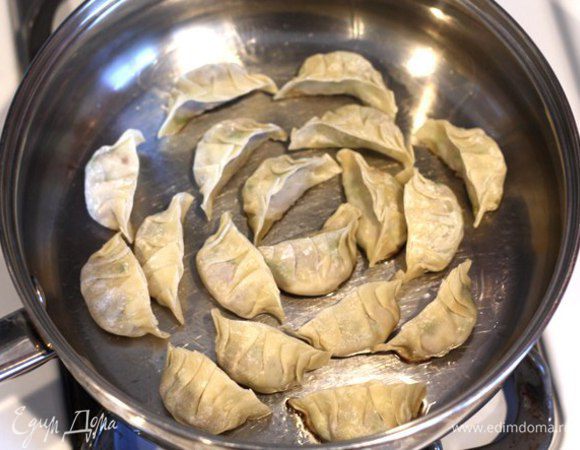 Добавляем в разогретую на среднем огне сковородку 1 ч. л. кунжутного масла. Аккуратно выкладываем пельмени Gyoza в сковородку. Обжариваем их на плоской стороне.