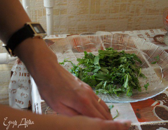 На большое плоское блюдо выкладываем рукколу, которую просто рвем руками, немного сбрызгиваем оливковым маслом и бальзамическим уксусом