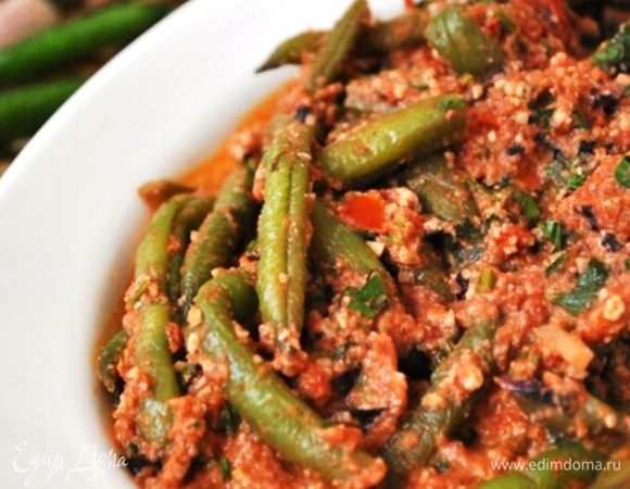 В сотейник положить лук, томаты, фасоль, ореховую заправку, зелень и тушить 10 минут.