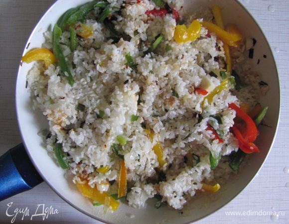 Рис тщательно промыть, слить воду, добавить в сковороду с луком и чесноком. Рис немного прожарить до легкой прозрачности. Добавить порезанный болгарский перец, острый перец и натертую на терке морковь.(Морковь - не обязательный ингредиент). Помешивая, потомить еще минут 7.