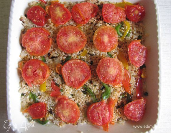 На дно огнеупорного блюда выложить порезанные кружочками помидоры, затем рисовую смесь и опять кружочки помидор. Залить стаканом воды, накрыть крышкой и поставить в предварительно разогретую духовку минут на 20. Вода должна впитаться.