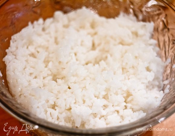 Рис тщательно промываем. Заливаем водой в соотношении 1,5 части воды к 1 части риса и ставим на самый большой огонь. Дожидаемся, пока почти вся вода не выкипит и из-под риса пойдут пузыри, уменьшаем огонь до минимального, накрываем кастрюльку крышкой и оставляем на 10 минут. Затем снимаем с огня, не открывая крышку и оставляем выпариваться рис еще на 15 минут. Выкладываем его в неметаллическую соду, вмешиваем рисовый уксус и оставляем остывать до комнатной температуры