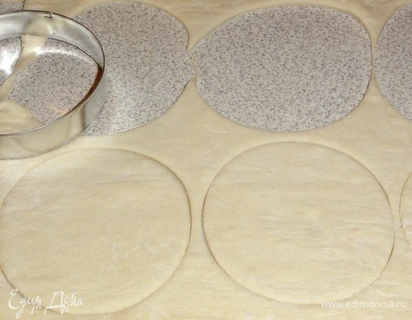 Размороженное слоеное тесто раскатайте в пласт прямоугольной формы толщиной примерно 3 мм. Круглой формой диаметром 9 см (у меня 8,5) вырежьте из теста 20 кругов. Делайте это не оставляя  обрезков. 