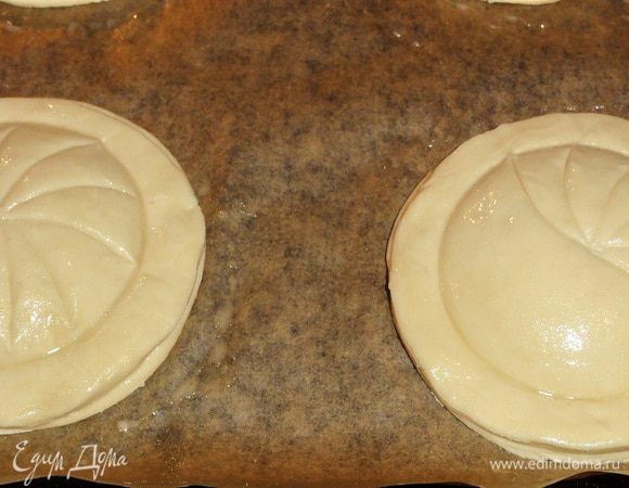 Теперь поверхность пирогов смажьте яйцом и нанесите рисунок тыльной стороной ножа.