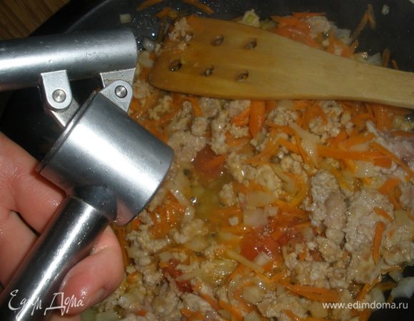 Выложить к фаршу лук с морковью и помидор. Выдавить чеснок. Посолить и поперчить. Все перемешать. Тушить примерно 5 минут без крышки, чтобы вытопилась лишняя влага. 