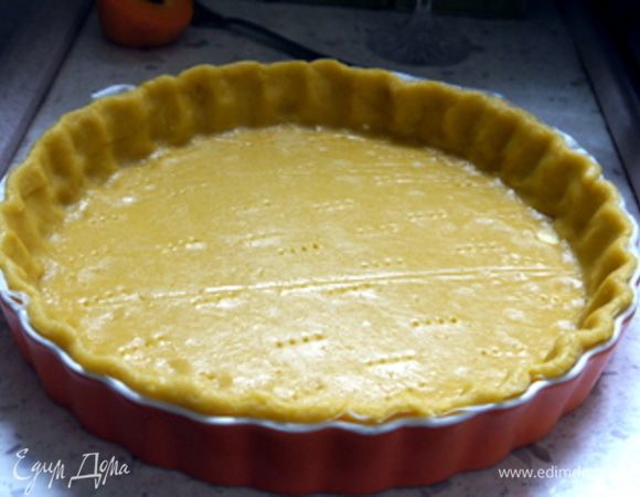 Достать охлажденное тесто и раскатать его между двух листов пергамента. Поместить тесто в форму для выпечки диаметром 24 см. Наколоть вилкой.