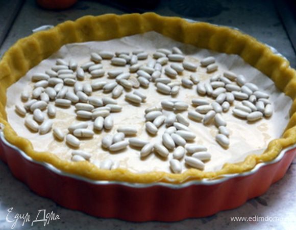 Накрыть листом пергамента и всыпать немного сухой фасоли или гороха. Выпекать при 180°С около 10 минут.