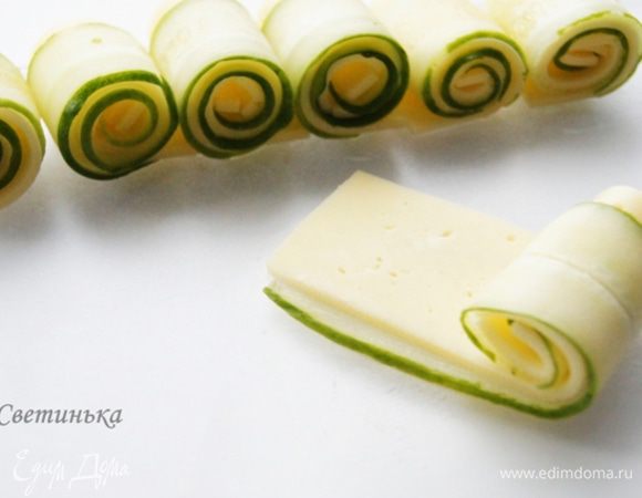Сыр желательно приобрести в нарезке, тогда процесс готовки еще больше упрощается. Во всех иных случаях, нарезайте тоненько, как только сможете. После этого кладем сыр на огурец и начинаем скручивать рулетики.