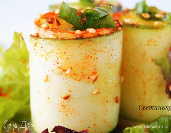 Осталось только выложить салатные листья на тарелку. На них ставим сырно-огуречные рулеты. Брызгаем на них оливковым маслом, посыпаем кунжутом и сладкой паприкой.
