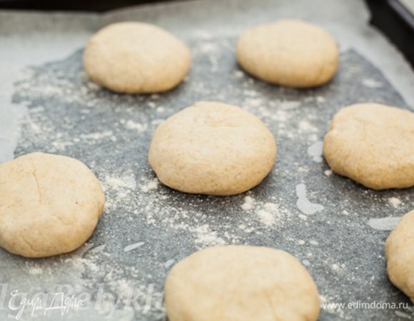 Когда тесто поднялось второй раз, сформировать из него небольшие плоские булочки, примерно 7-8 см в диаметре. Выложить их на смазанный маслом, застеленный пергаментом противень и присыпанный мукой противень. Оставить минут на 15 для расстойки.
