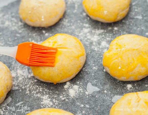 Теперь смазать булочки желтком, сделать на них глубокие крестообразные надрезы.