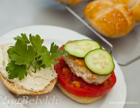 Сверху помидора положить котлету, 2 кружка огурца и листики петрушки. Накрыть второй половинкой булочки. Подавать сразу на стол.