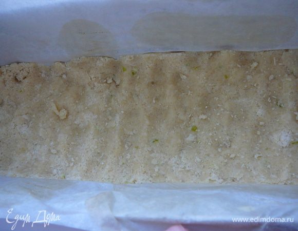Форму застелить пергаментом. Тесто разделить на две половины. Одну часть теста выложить в форму и утрамбовать.