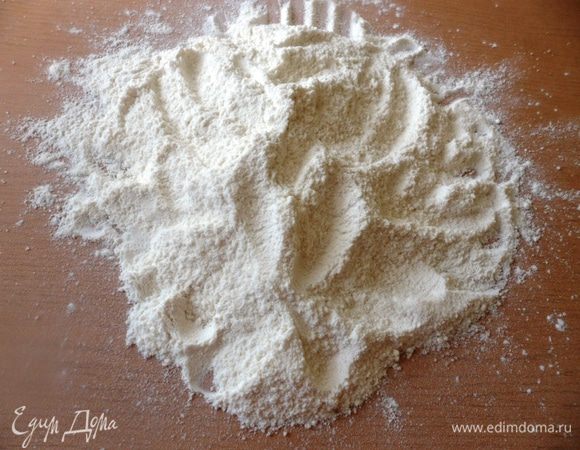 Просеять муку на разделочную доску. Добавить соль и сахар.