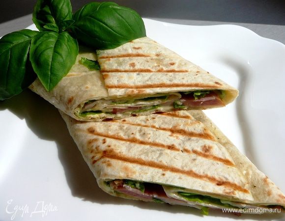 На смазанную соусом лепешку выложить салатные листья, ломтики ветчины и сыра, свернуть рулетом. Такос можно подавать сразу, а можно обжарить на сковороде-гриль. Приятного аппетита!