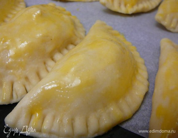 Выложить пироги на противень, застеленный пергаментом, смазать взбитым яйцом.