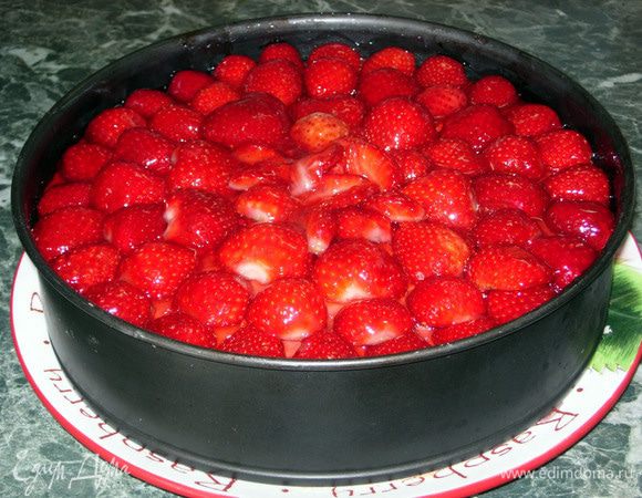 Разрезать и пропитать бисквит сладким сиропом, вкус на Ваше усмотрение. Накрыть его вторым слоем и снова нанести крем. Крем слегка посыпать крахмалом, чтобы он впитал клубничный сок, и поместить этот сандвич в кольцо от формы для выпечки. Укладываем клубнику от центра к краям.