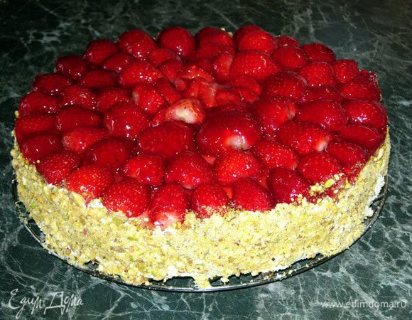 Вынимаем наш бисквит из формы. Смазываем края пирога остатками крема и украшаем тёртыми фисташками.
