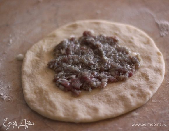 Возьмите столовую ложку фарша и выложите на "блинчик". Разровняйте фарш. Диаметр "мясного блинчика" должен быть в два раза меньше.