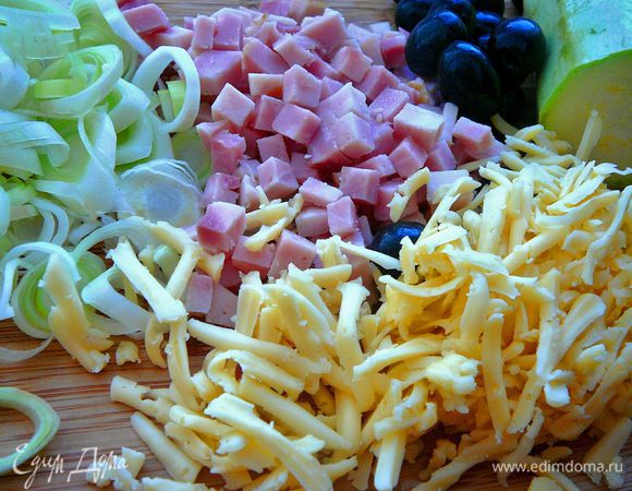 Подготовить начинку. Сыр натереть на крупную терку. Лук порей порезать тонкими кольцами и обжарить на медленном огне на оливковом масле, добавив зубчик мелко рубленного чеснока. Лук обжаривать до мягкого состояния. Я слегка обжарила, затем прикрыла крышкой на 2 минуты. Ветчину нарезать мелким кубиком. Маслины, если есть косточка, достать ее, и порезать мелко.