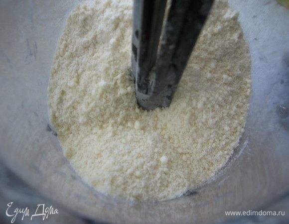 В чашу блендера поместить муку, половину сахара и масло. Измельчить до образования крошки.
