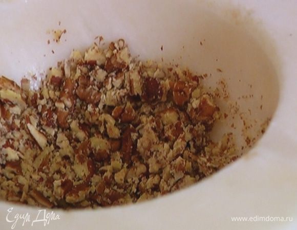 Большую часть орехов измельчить в ступке, чтобы остались небольшие кусочки, добавить в тесто и перемешать.