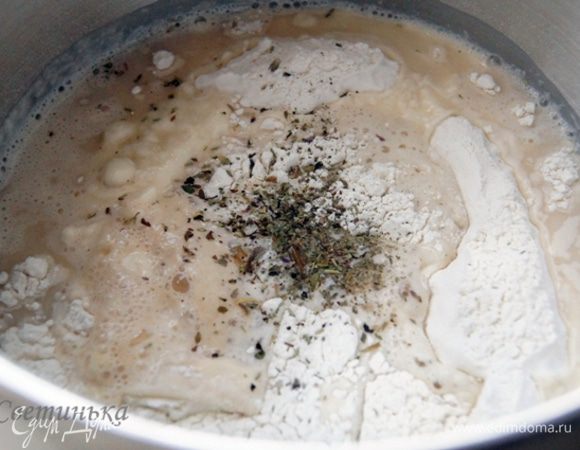 Муку просеять, добавить соль, травки. Сделать воронку, влить в нее оставшуюся воду, масло и возродившиеся дрожжи. Далее миксер в дело. Тесто должно получиться очень упругое и не липнущее к рукам.