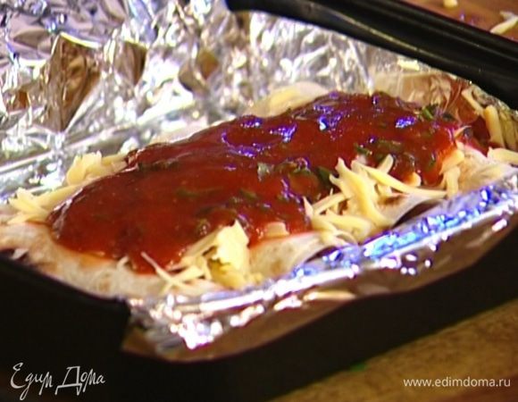 Глубокий противень застелить фольгой, уложить в него буррито, присыпать сверху оставшимся сыром, полить соусом и отправить в разогретую духовку на 15 минут.