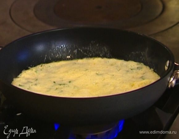 Разогреть в сковороде 1 ч. ложку сливочного и 1 ч. ложку оливкового масла, влить половину яичной массы и равномерно распределить. Как только края схватятся, накрыть сковороду крышкой и убавить огонь.