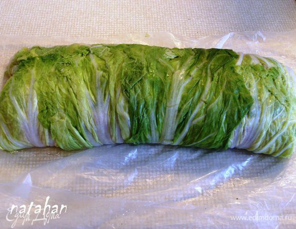 Аккуратно, помогая себе через пищевую плёнку, сформировать рулет.  Перекатить его по плёнке так, что бы стык длинных сторон оказался внизу. Боковые листья заправить вовнутрь рулета. Полуфабрикат голубца готов. 