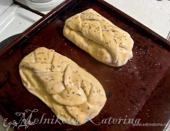 Выложить булки на противень, смазанный сливочным маслом. Накрыть тканью и поставить в теплое и укромное место для расстойки примерно на 20-30 минут. После этого смазать булки яичным желтком, посыпать сверху тмином. 