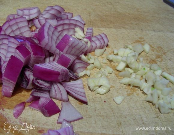 Лук и чеснок шинкуем. В кастрюле разогреваем оливковое масло и обжариваем их пару минут.