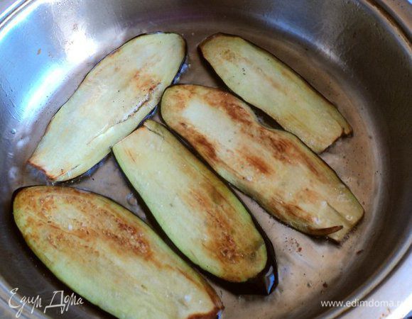 На сковороду налить оливковое масло, нагреть и положить порезанный пластинками чеснок, поджарить и затем вынуть чеснок. Поджарить баклажаны  до слегка золотистой корочки, выложить на тарелку.