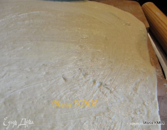 После этого тесто обмять, разделить на две разные части.
Раскатать каждую часть в пласт, равномерно смазать сливочным маслом.
