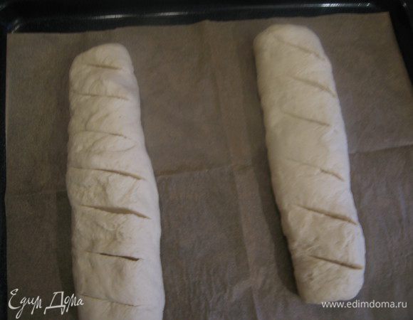 Противень выстелить бумагой, выложить батоны швом вниз, подравнять. Сделать характерные надрезы. Я делаю зубчатым ножом 