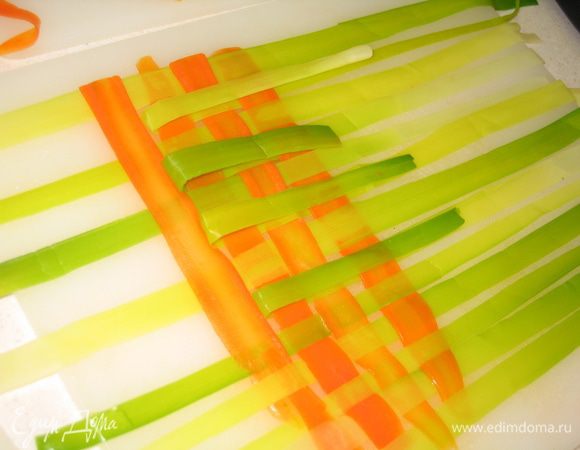 Сплести плетенку из подготовленных овощей. Несколько советов: сначала следует разложить лук-порей, а затем от середины начать вставлять морковь. Для облегчения этой процедуры следует загибать от края к центру луковые ленты через один...на оставшиеся ленты положить морковную и вернуть все на свои места. так повторять еще и еще, каждый раз меняя четные и нечетные ряды луковых лент