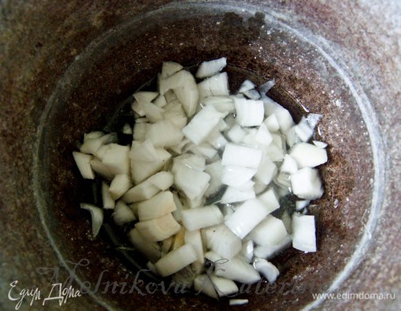 Икру готовить нужно в глубокой кастрюле с толстым дном или чугунном казанке. Я готовила в казанке. Разогреть в нем масло. В это время нарезать кубиками лук и добавить к маслу. Пассеровать 1-2 минуты, чтобы он пустил сок, но не зажаривался. 