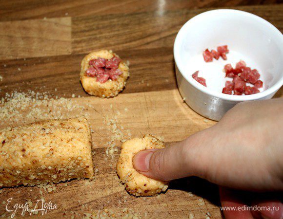 Перчённое тесто скатать в колбаски(d=2-3 см),смазать чуть взбитым белком и обвалять в грецких орехах.Нарезать колбаски на шайбочки,пальцем сделать в каждой из них углубление,чуть смазать белком и выложить солёную начинку(кусочки колбасы,бекона и т.д.).