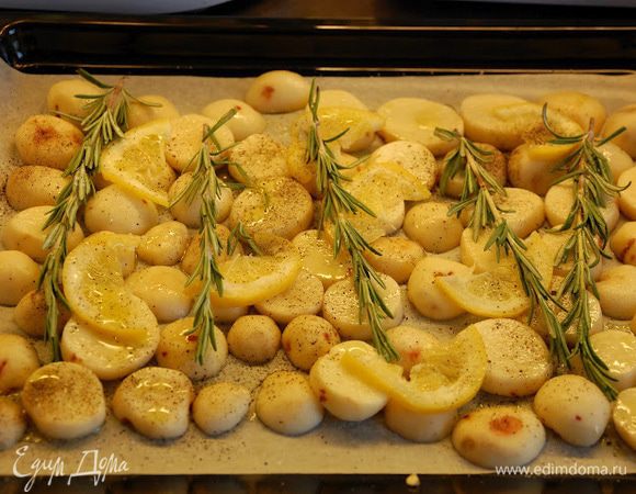 В это время очистите картофель. Нарежьте кружками по 0,5 см толщиной. Нарежьте колечками оставшуюся половину лимона. Противень застелите пергаментом. Смажьте каплей оливкового масла весь лист. Разложите картошку. Сверху на картошку произвольно выложите кольца лимона и веточки розмарина. Посыпьте солью, перцем и полейте оливковым маслом. На эту красоту выложите ребра в маринаде. Если в миске остался маринад, распределите его по мясу. Отправьте в духовку на средний уровень на 25–30 минут.