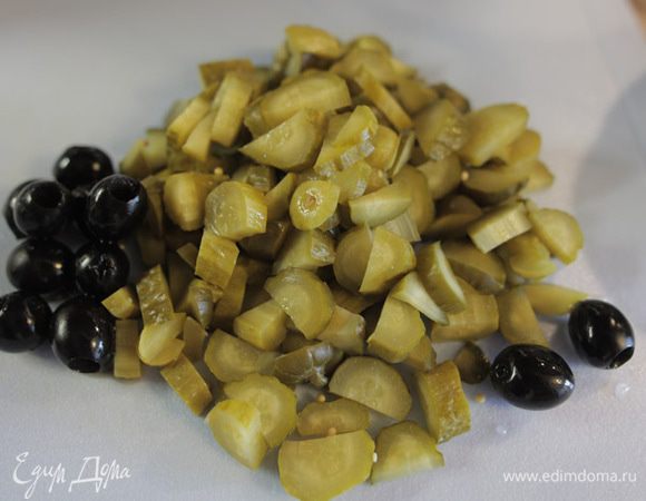 Нарежьте огурцы. Если маслины без косточек, то их можно разрезать пополам.