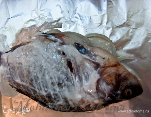 На кусок фольги выложить рыбу. Смазать ее сметаной, перевернуть и смазать второй бок. 