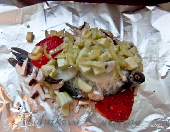 На рыбу выложить овощи. Их слегка посолить, посыпать орегано. Сбрызнуть все растительным маслом. 