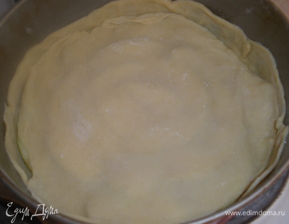 Раскатываем один из маленьких кусочков теста и накрываем им яблоки. Смазываем сливочным маслом.