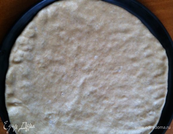 Тесто рассказать в тонкий пласт, положить на противень или специальную форму для пиццы