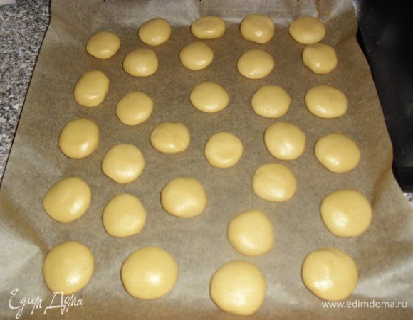 Разделить тесто на 3 части. Одну часть раскатать на столе в круг и сделать корж, уложить в противень, подравнять края, лишнее срезать. Из оставшегося теста формируем шарики по 3 см и раскладываем на протвень, выстланный бумагой для выпечки.