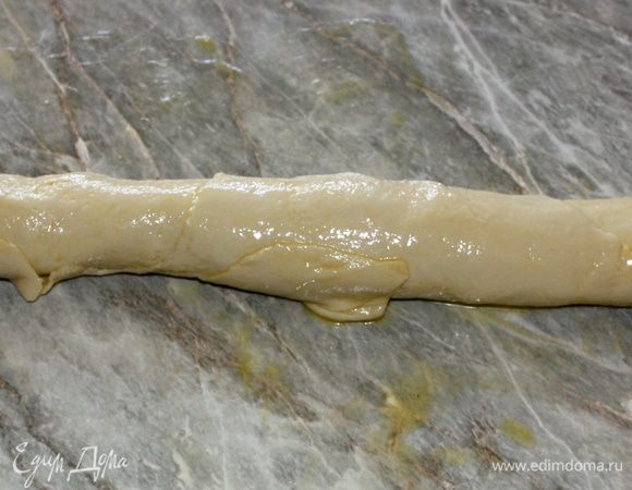 Скатайте тесто с маслом в тугой жгут. Скатывая, старайтесь немного оттягивать тот край, с которого заворачиваете, чтобы еще немного растянуть тесто.