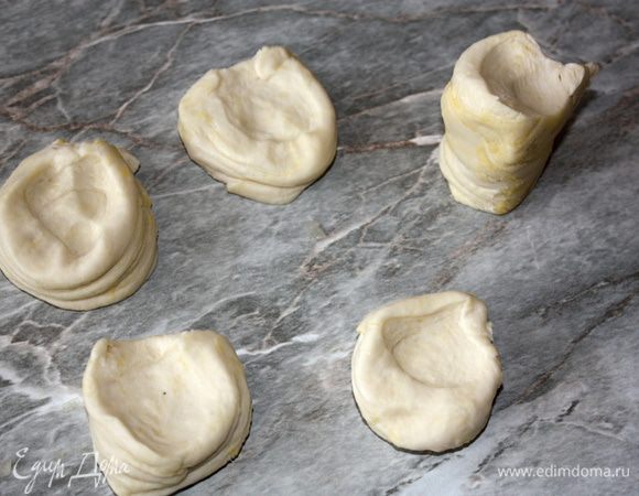 Кусочки теста сожмите поперек разреза, так чтобы его спираль была в середине образовавшейся лепешки, и начинайте быстро раскатывать эту лепешку, пока не получится очень тонкий круг 15 см в диаметре. Тесто будет очень упругое, поэтому старайтесь его не переворачивать, т. к. оно будет сжиматься. Обратите внимание, что здесь поверхность стола мукой присыпать не надо. А еще лучше держать под рукой чистую тряпочку, чтобы убирать излишки масла со стола. Стол должен быть все время сухим и чистым, чтобы при раскатке тесто на нем лучше фиксировалось.