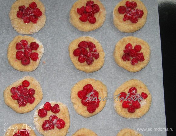 Из каждого кусочка руками сформировать коржик толщиной 1 см. Присыпать сахаром, в центр выложить малину.